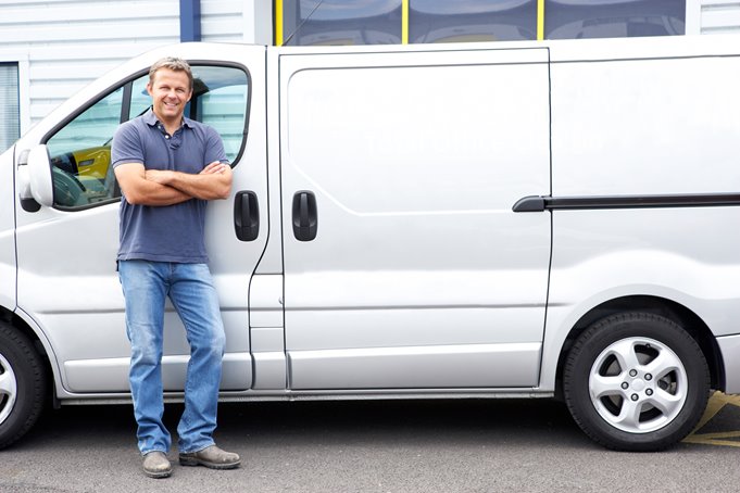A smiling man leaning against his van