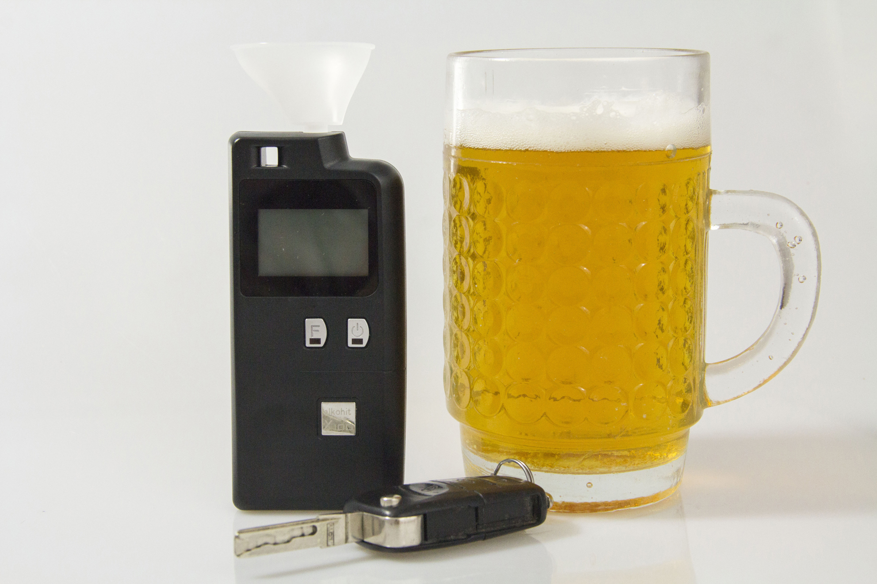 A breathalyser next to a car key and a pint of beer
