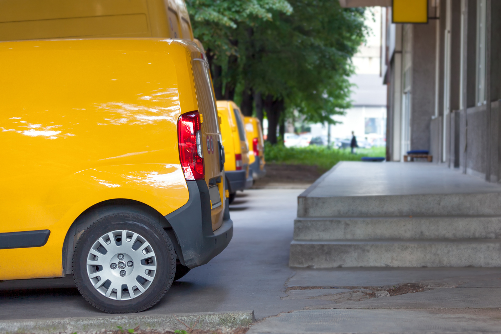 Three yellow vans parked next to each other in-front of a depot ready for deliveries