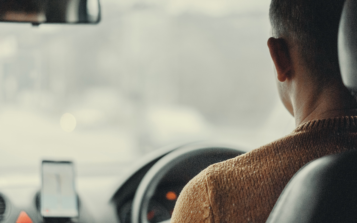 A view looking at the back of a man driving a car