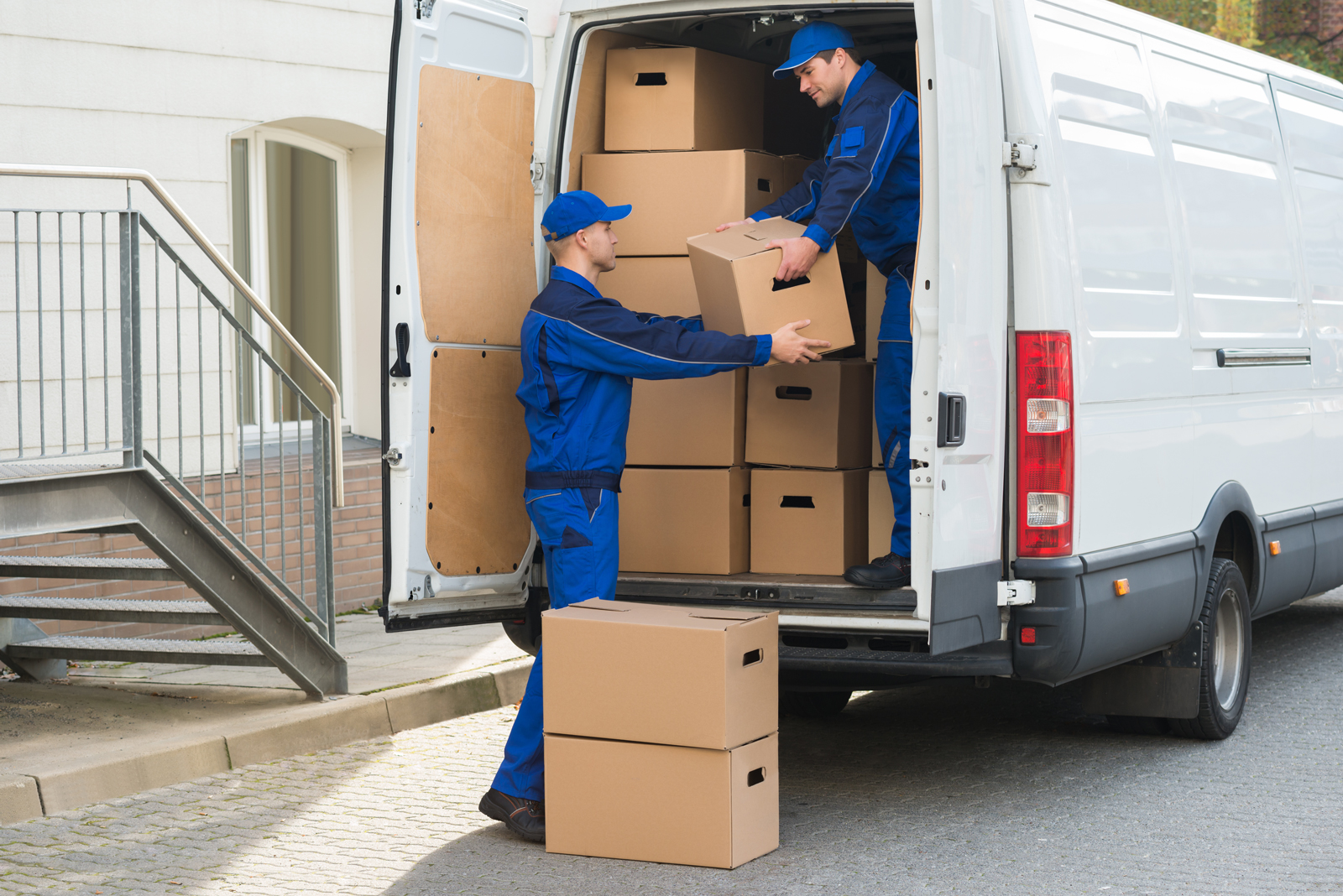 Two couriers unloading large boxes from the back of their van on a delivery