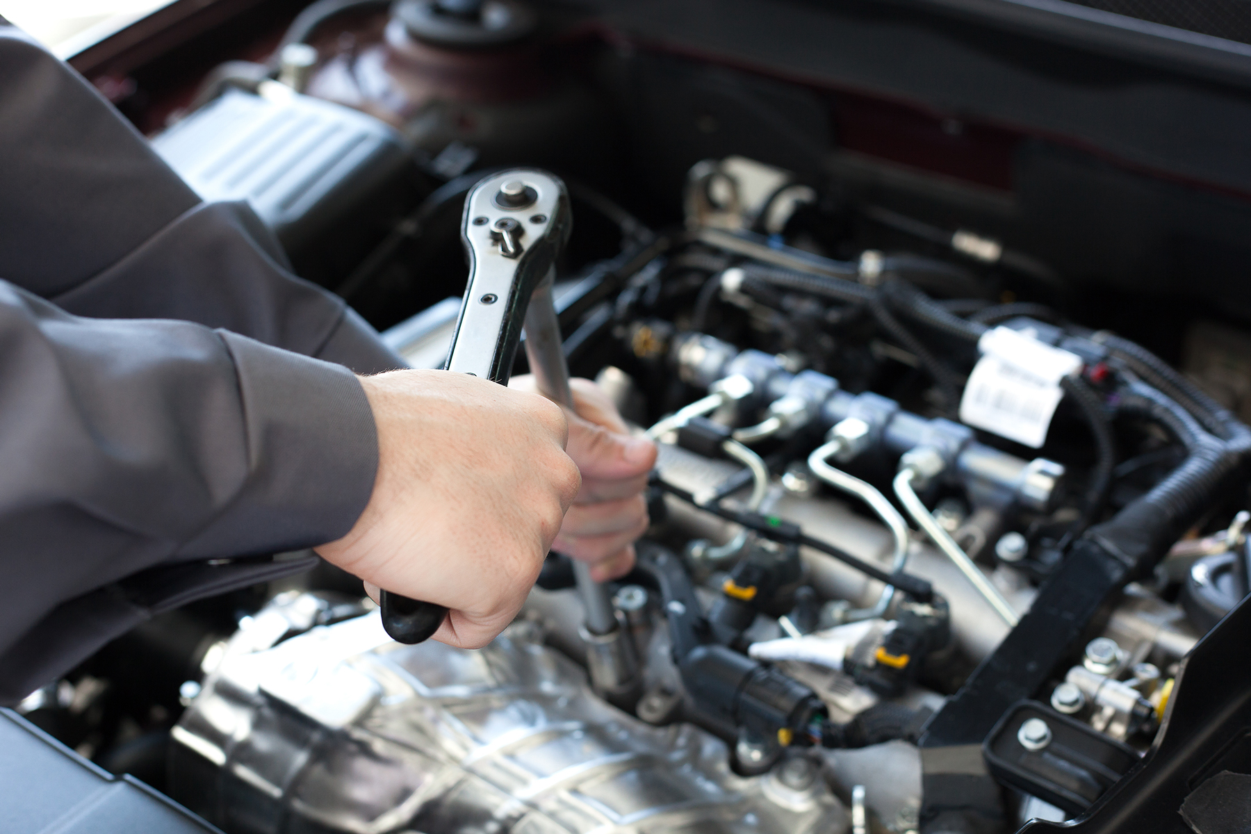 A mechanic working on an engine with a ratchet spanner