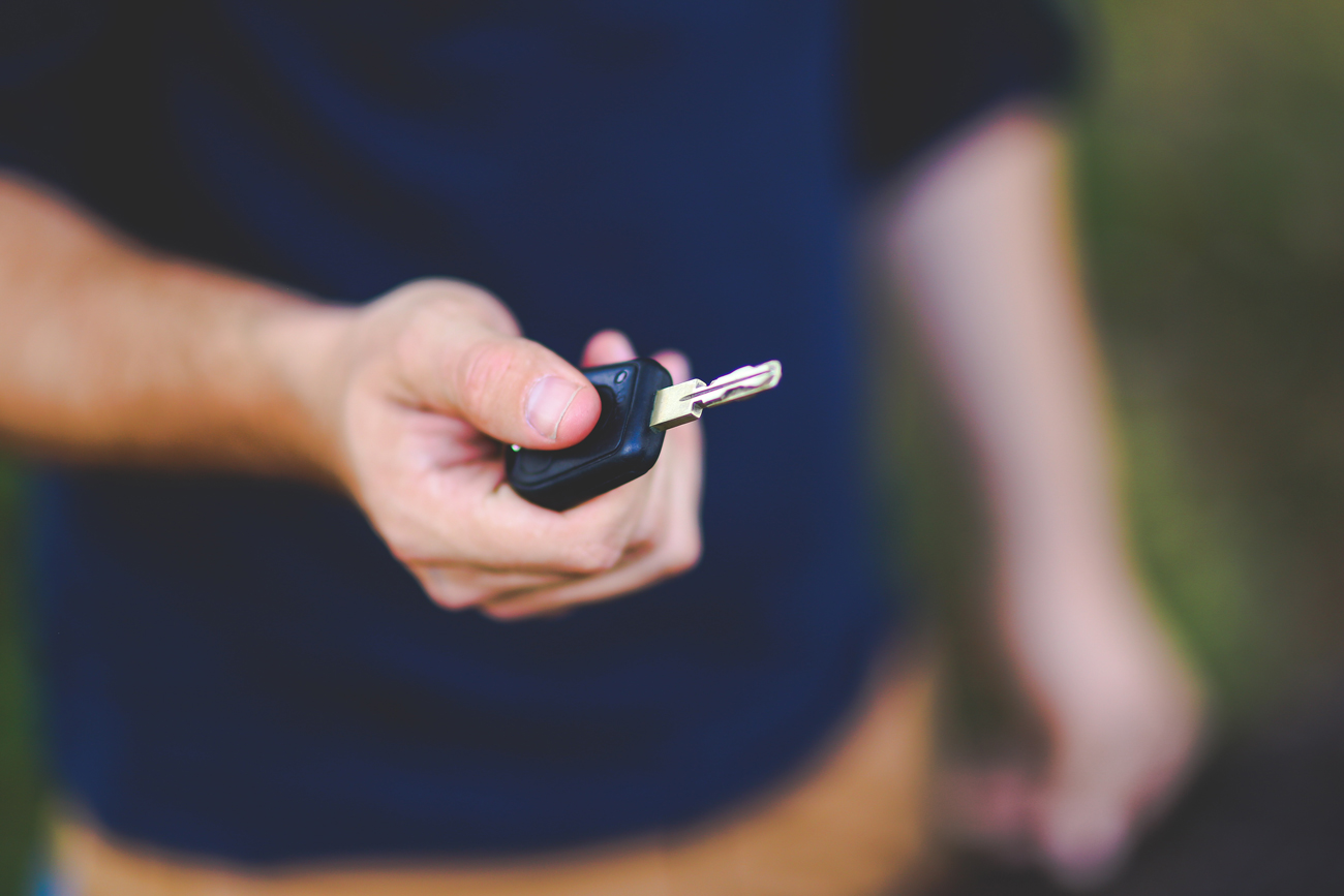 A man handing a car key towards the camera