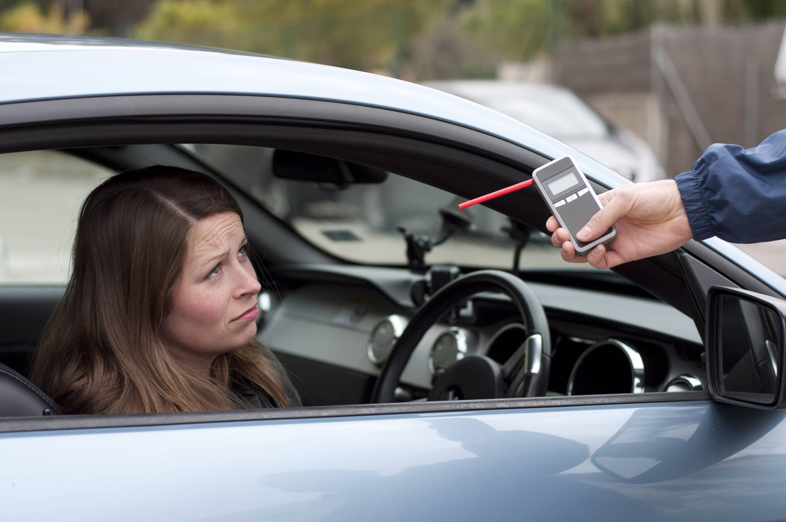A woman looking unhappy after failing a breathalyser test in her car