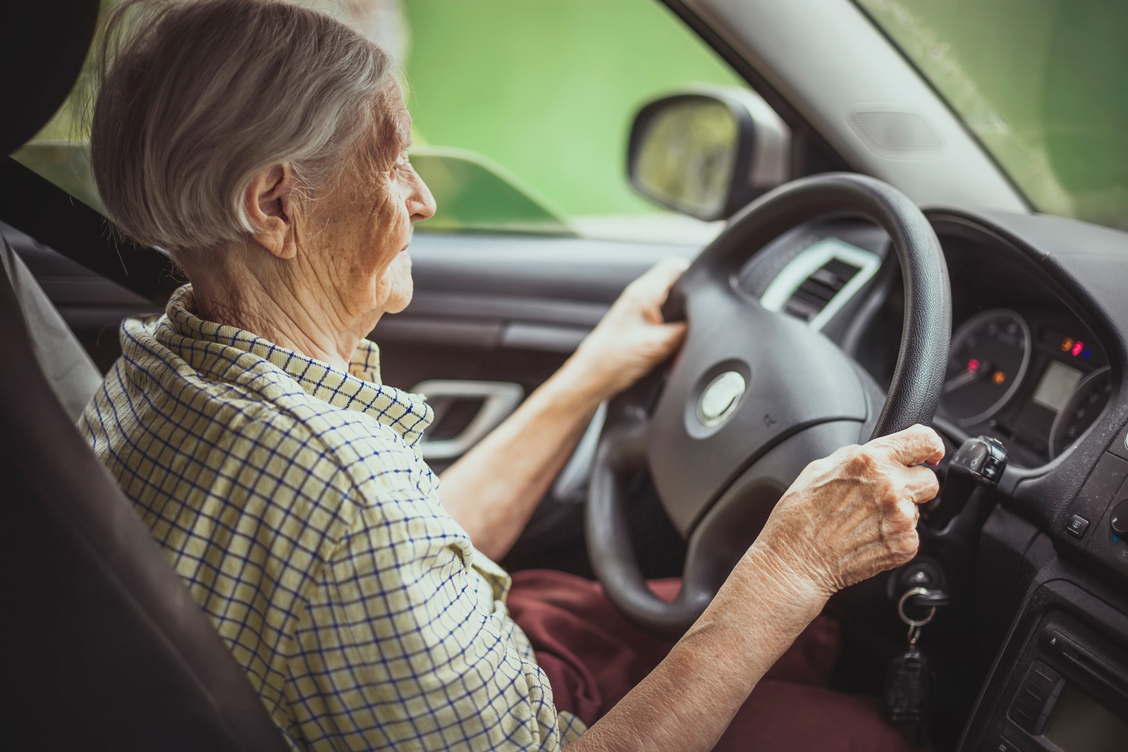 An elderly person driving a car