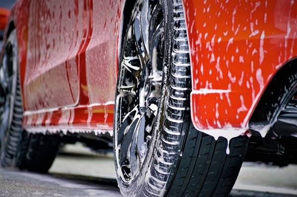 Red car covered in soap during wash