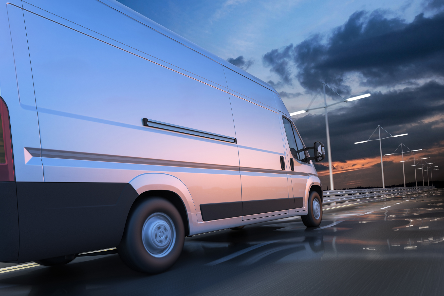 A silver van travelling along a motorway in the evening