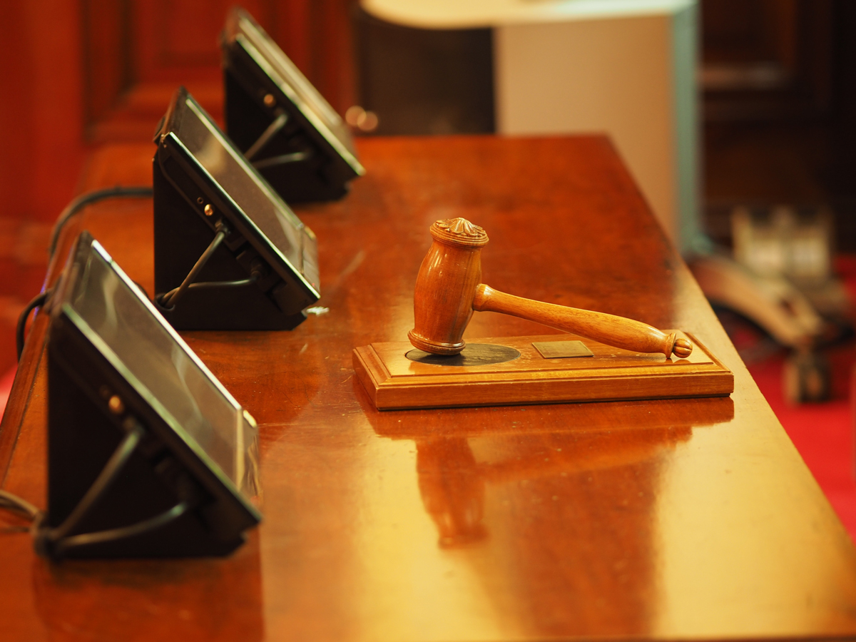 A desk at the front of an auction house with screens and a gavel