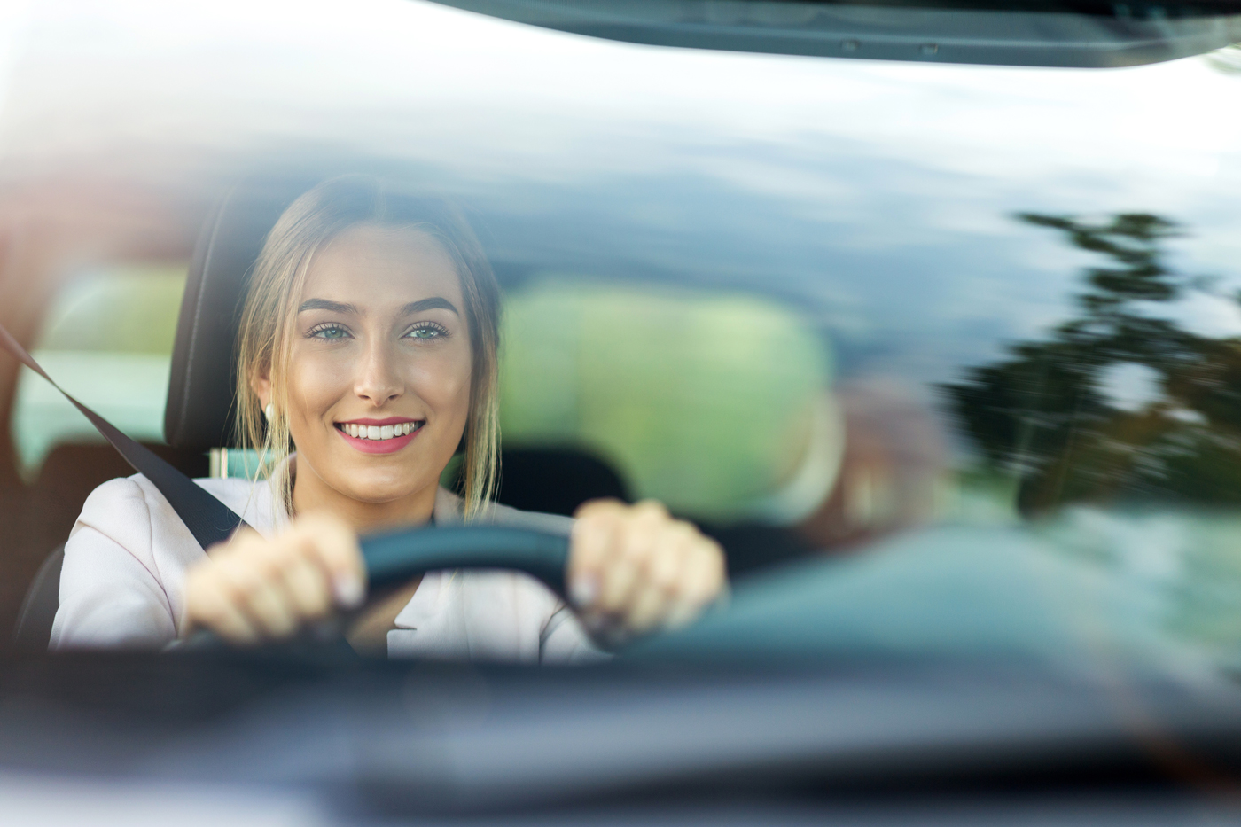 A young woman smiling as she drives her car