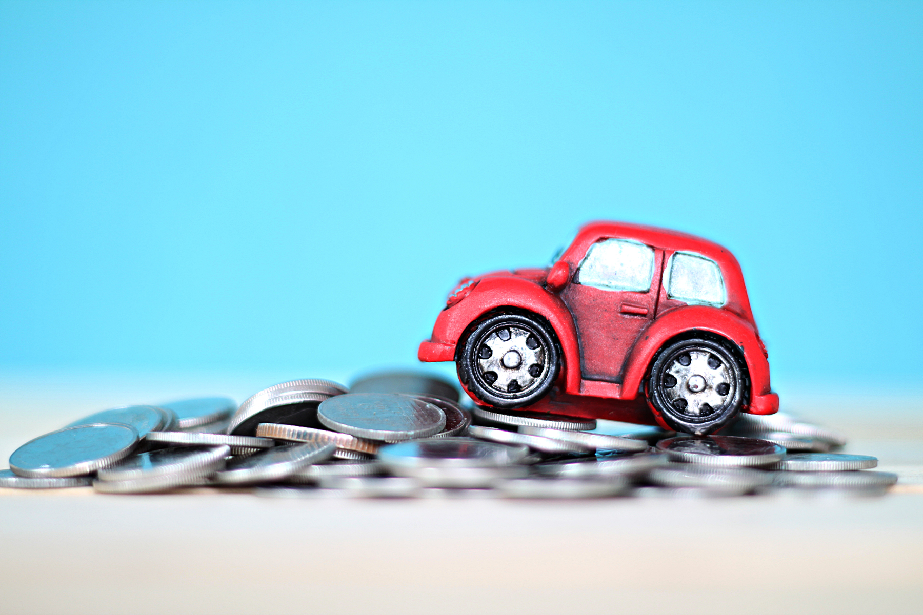 car-coins.jpg A model car placed on-top of a pile of coins against a blue background