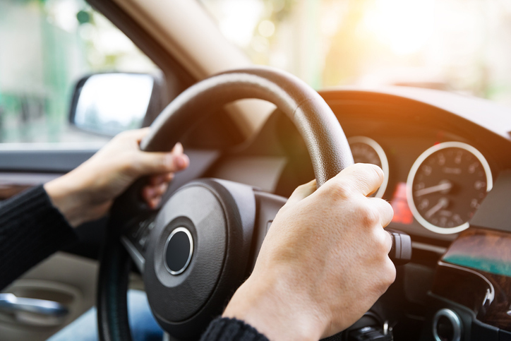 A person driving with 2 hands on the steering wheel