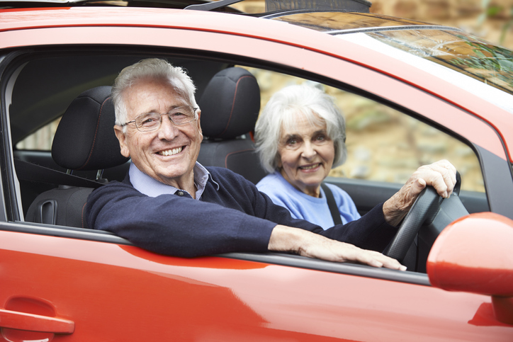 An older man driving his car with his wife