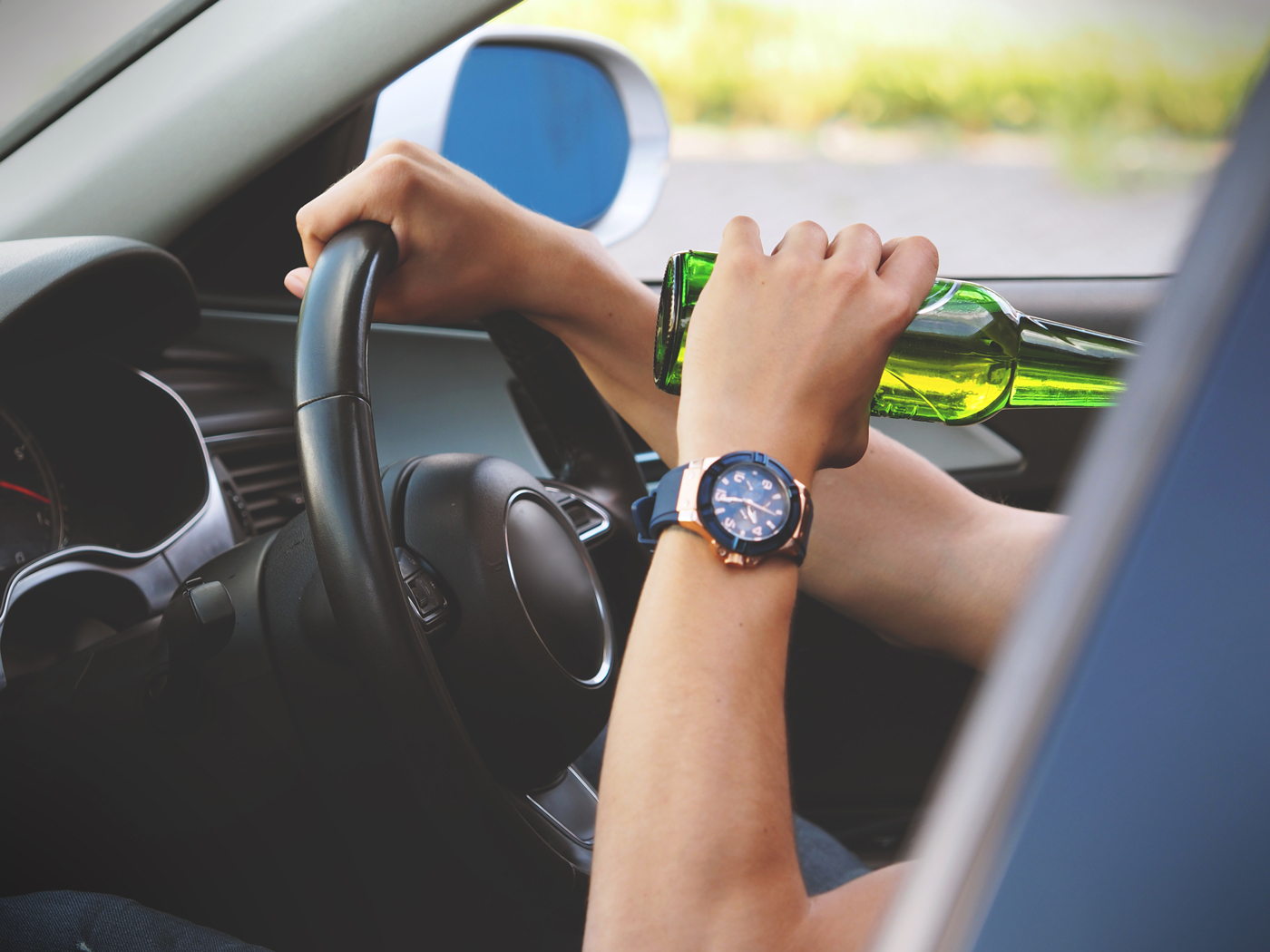 A man holding a beer while driving