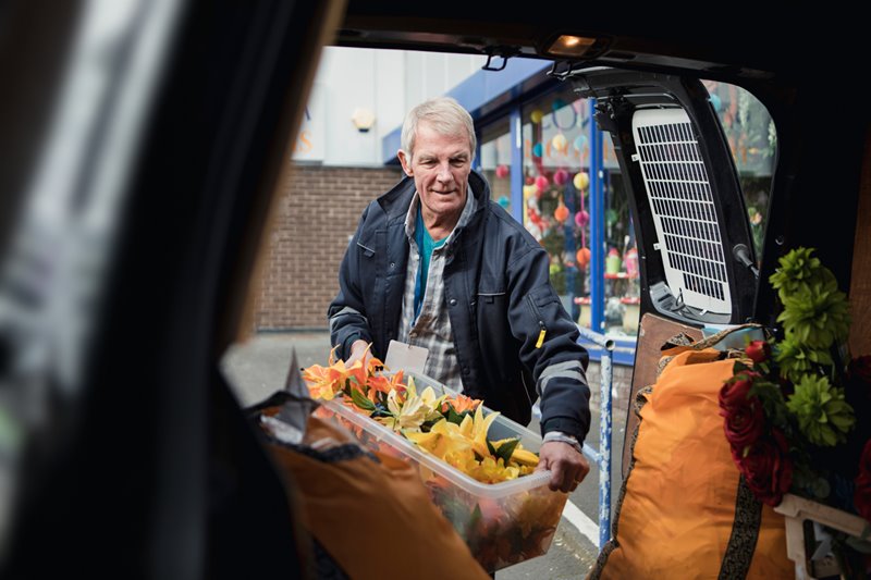 Man getting box of flowers out of the back of his van