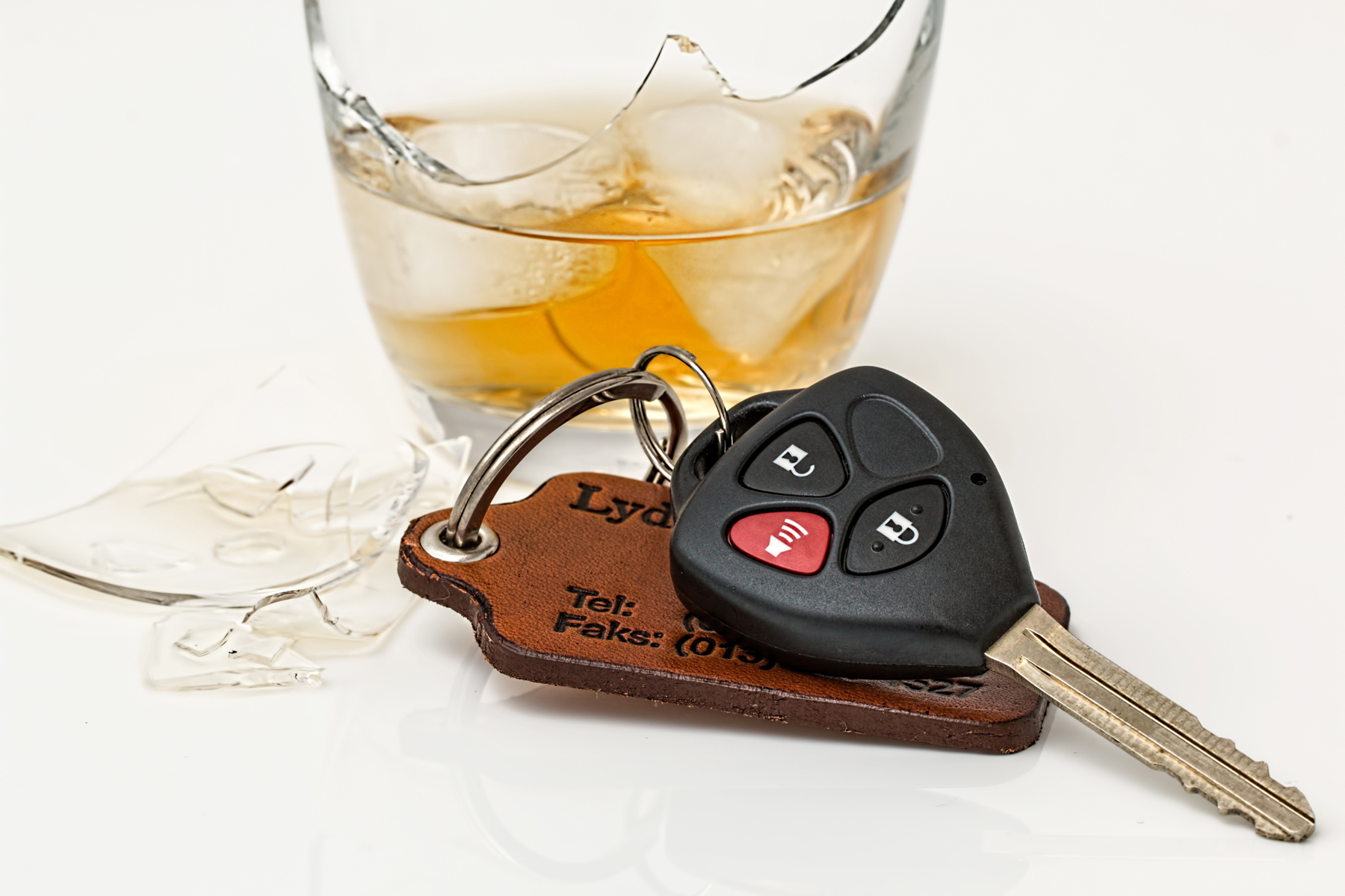 A broken glass of whiskey next to a set of car keys