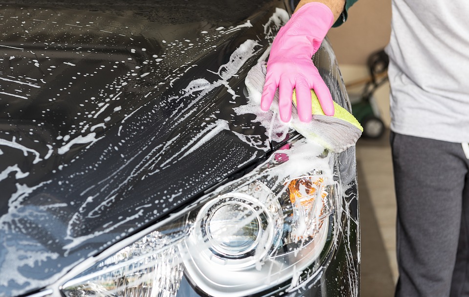 Someone with pink rubber gloves on cleaning the front of their van