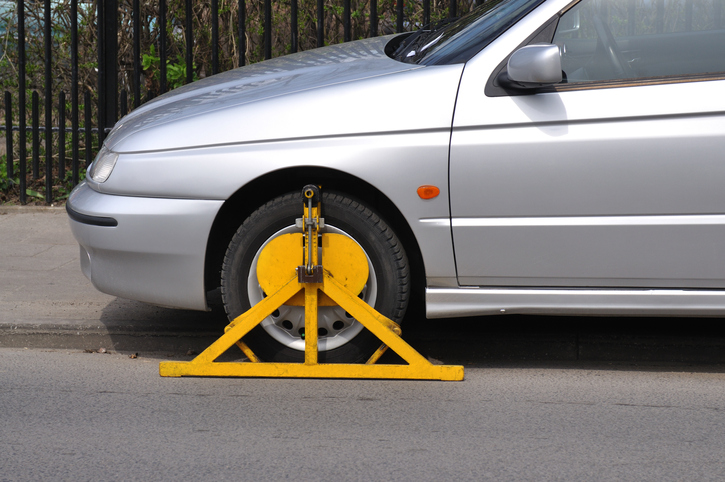 A clamped car parked on the curb side of a road