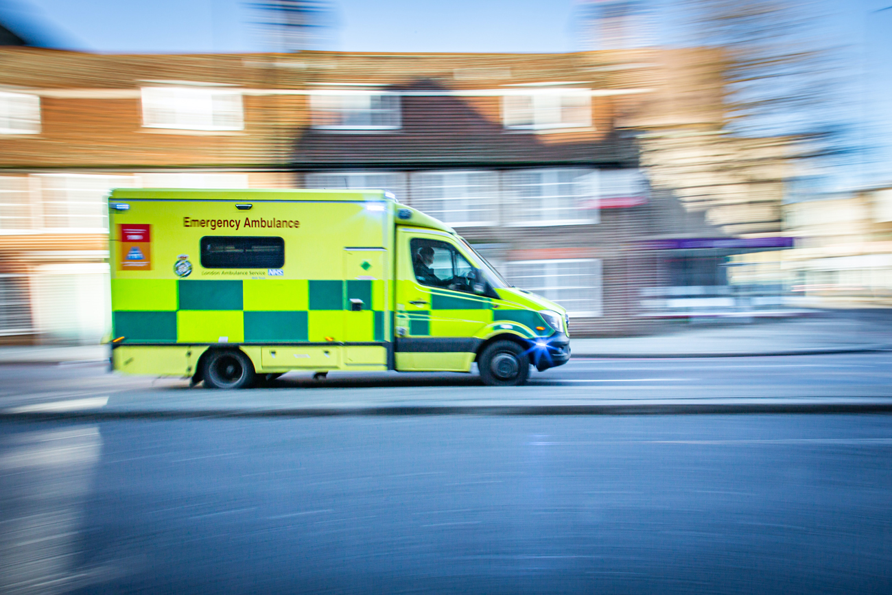 An ambulance travelling at speed with its lights and siren on
