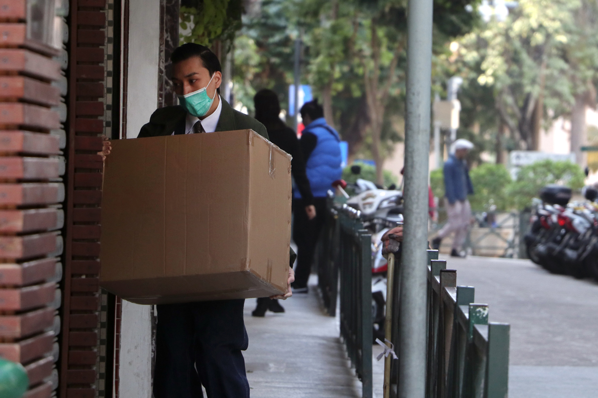 A delivery driver wearing a mask delivering a package to a door