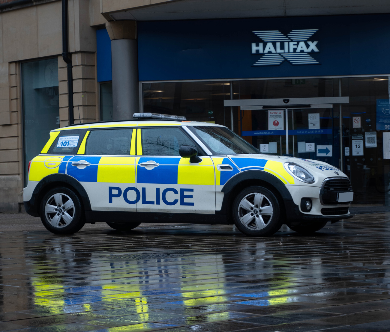 A police car parked on a pavement in-front of a bank