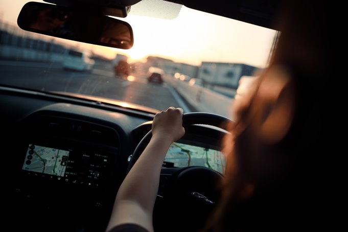 A girl driving a car along a motorway towards the sunset