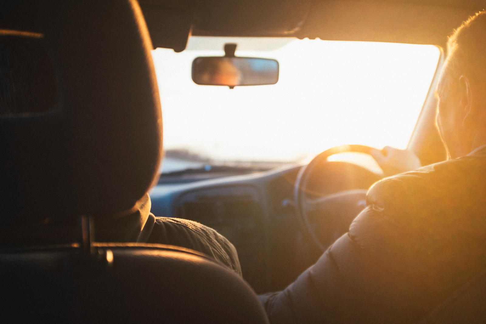 A person driving a car at sunset