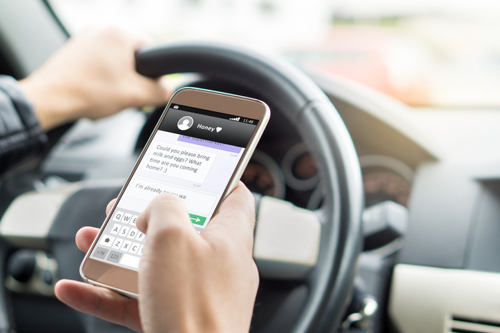 A person texting on their mobile phone whilst driving