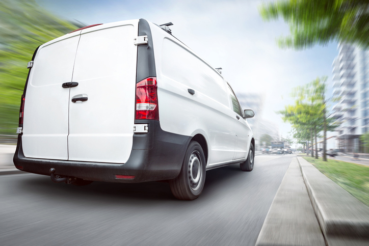 A silver van travelling at speed on a country road