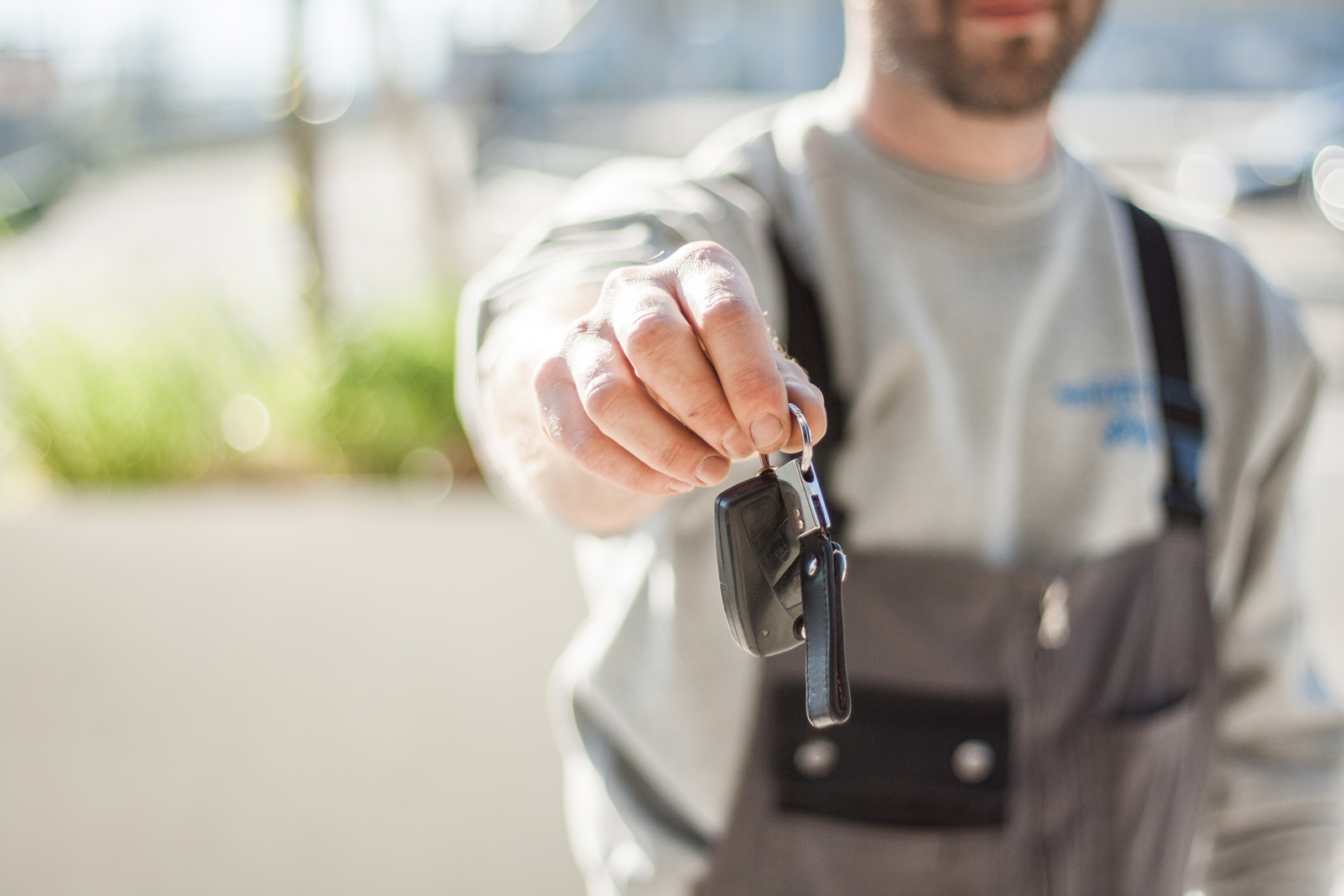 A mechanic wearing overalls holding up a customers keys