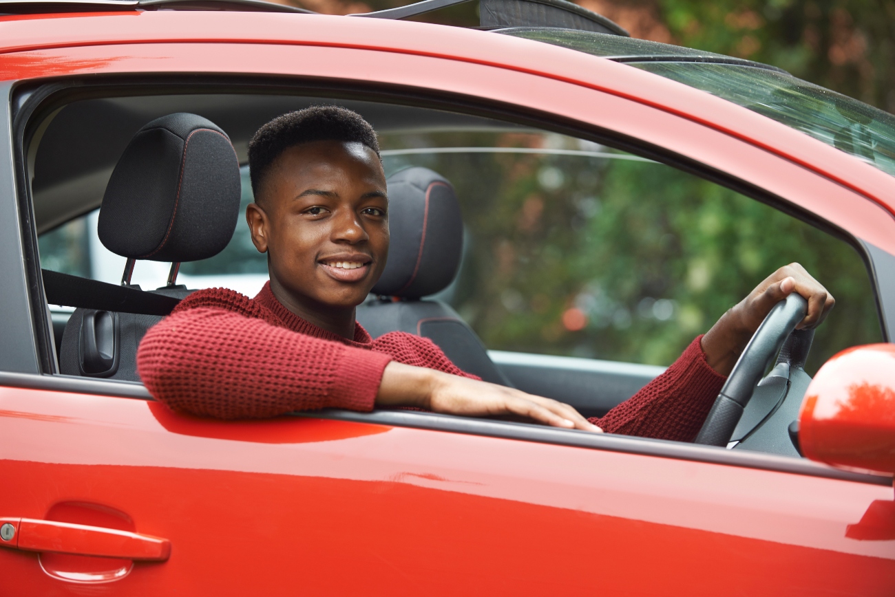 A-man-with-his-arm-placed-on-his-car-while-holding-onto-the-steering-wheel.jpg