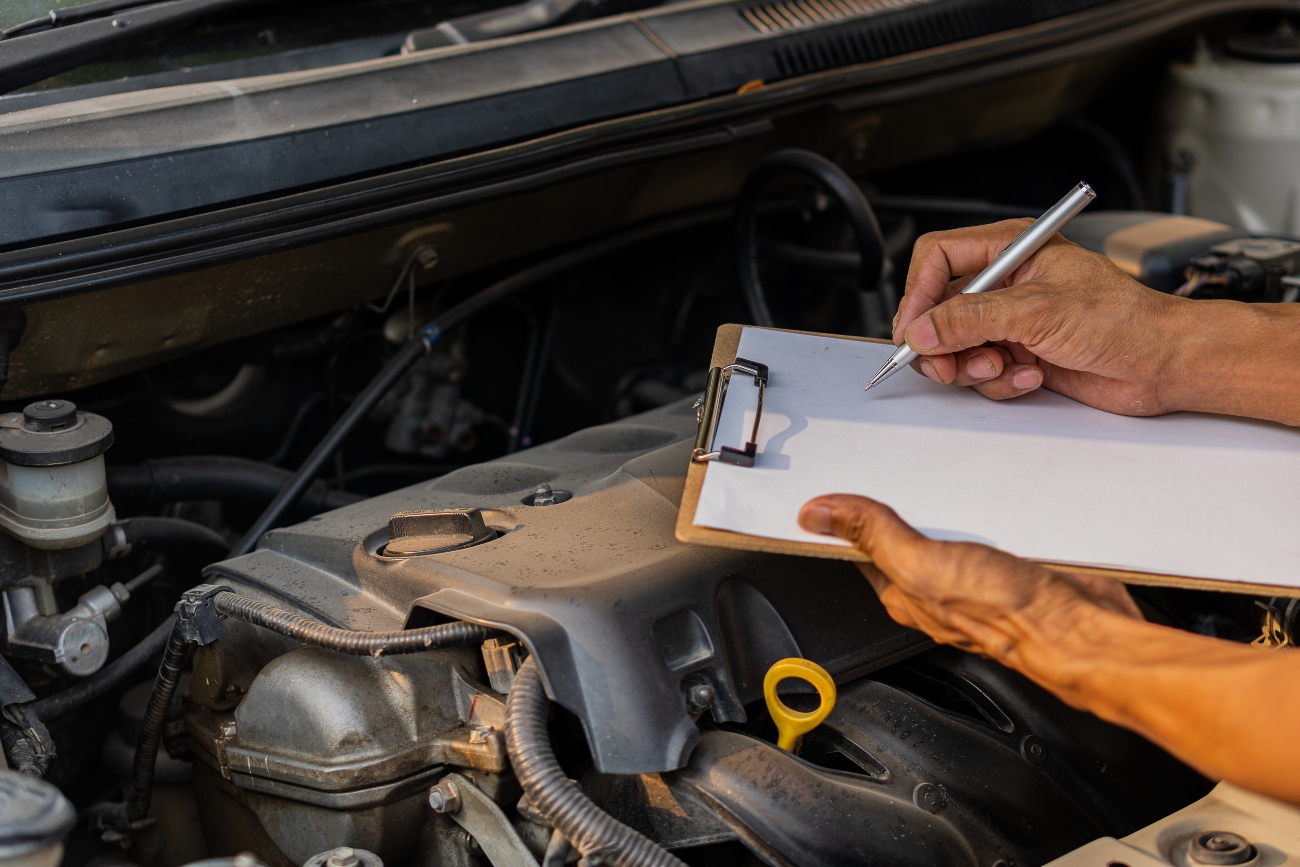 man-writing-on-a-piece-of-paper-over-a-car-engine.jpg