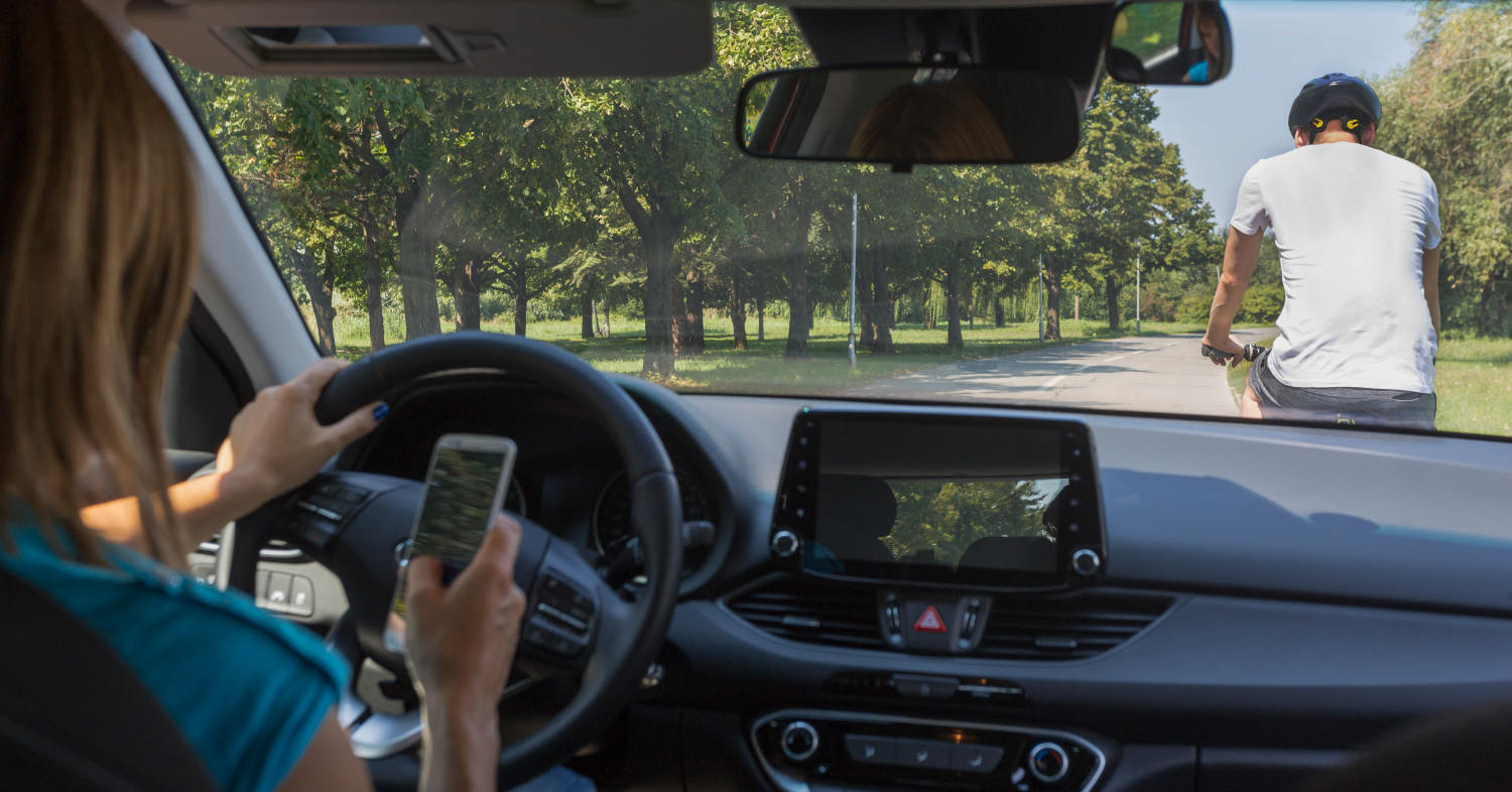 woman-using-her-phone-while-driving-and-is-close-to-crashing-into-a-man-on-a-bike.jpg