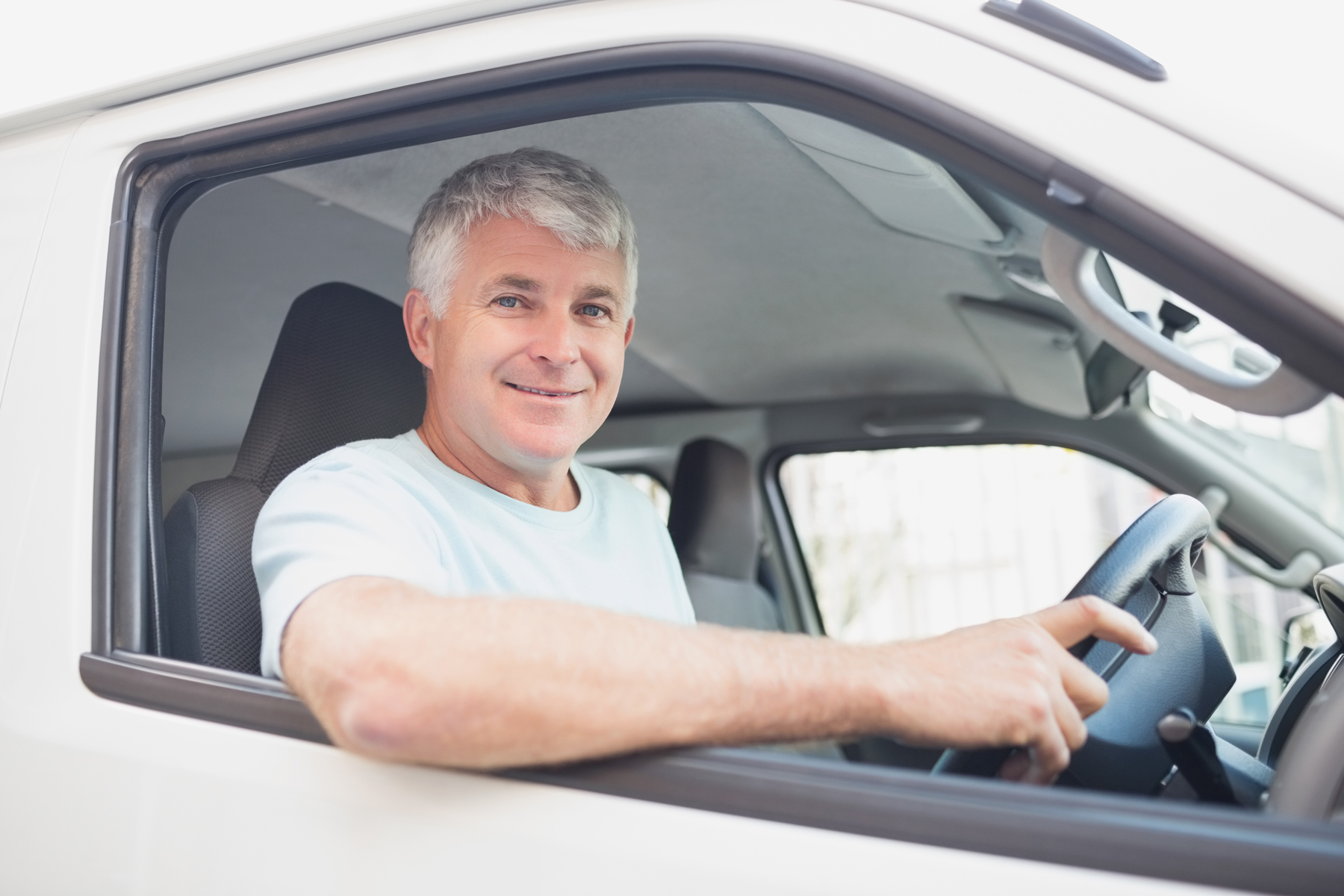 A man smiling while driving a van